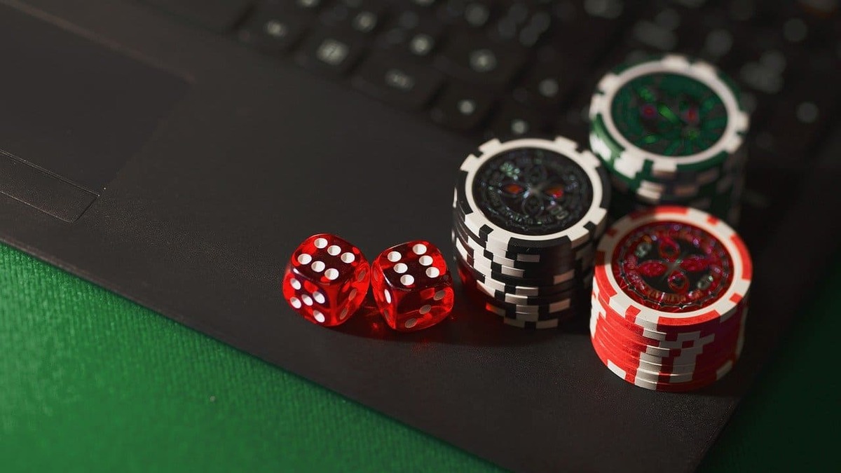 red dices and poker chips on a lap top